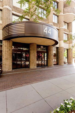 Front view of a multi-story building with cylindrical columns and large glass entrance.