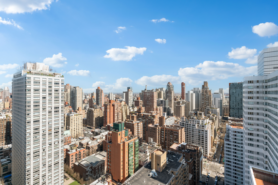 Panoramic view of a cityscape with multiple high-rise buildings under a blue sky with clouds.