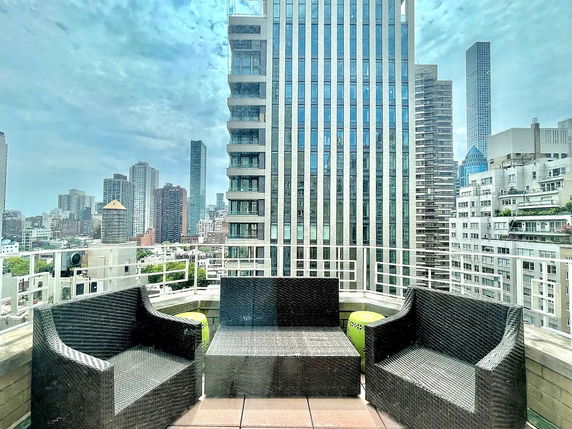 Rooftop with wicker chairs and skyscraper views.