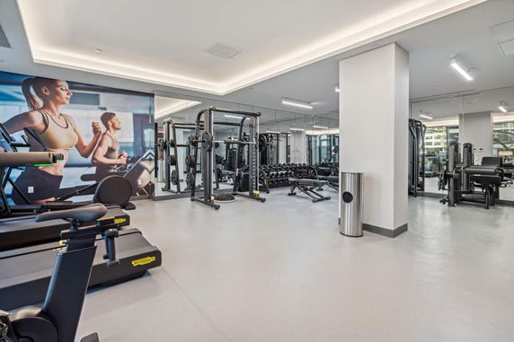 Interior view of a gym area with exercise equipment and mirrored walls.