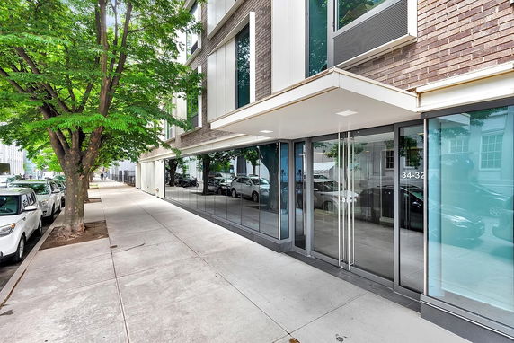 Street view of a modern building with glass windows and an entrance canopy.