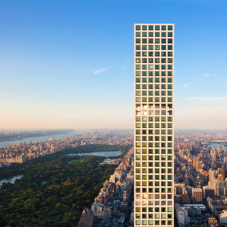 Tall skyscraper with a grid of windows overlooking a cityscape and park.
