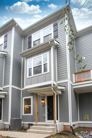 Front view of a three-story house with gray siding and black shutters.