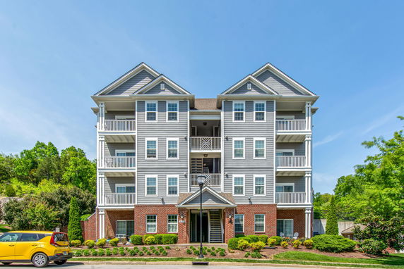 Front view of a multi-story residential building with balconies and a brick facade.