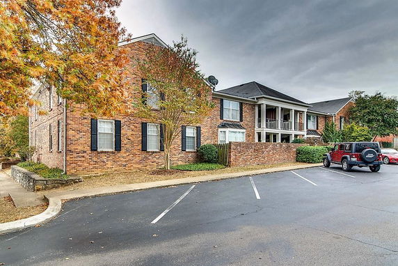 Front view of a brick two-story residential building with parked cars.