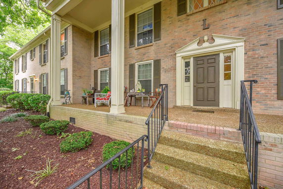 Front view of a two-story brick house with a covered porch and decorative columns.