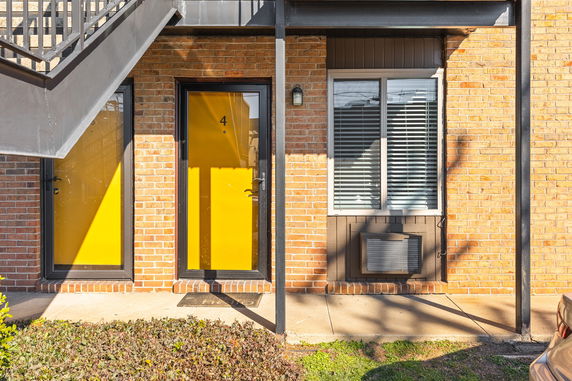 Front view of a building entrance with bright yellow doors and a window.