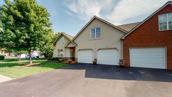 Front view of a house with three garage doors and a pitched roof.