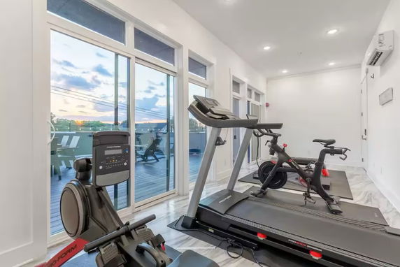 Indoor gym area with exercise equipment and large windows.