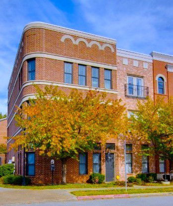 Front view of a multi-story brick building with arched windows and decorative trim.