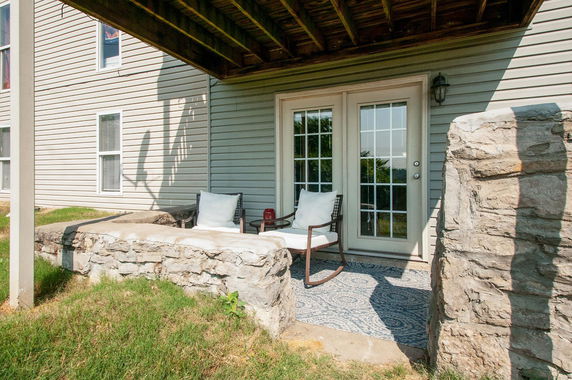 Exterior view of a house with a patio and stone wall.