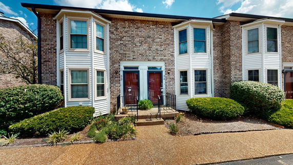 Front view of a two-story brick house with bay windows and dual entrance doors.