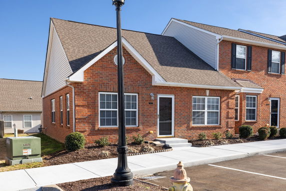 Front view of a brick single-story townhouse with gabled roof.
