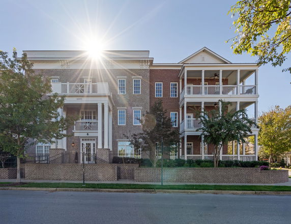 Front view of a multi-story brick building with multiple balconies and a prominent entrance.