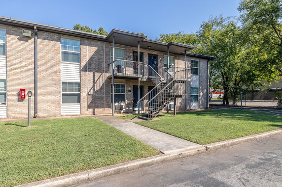Front view of a two-story apartment building with external stairs and brick facade.
