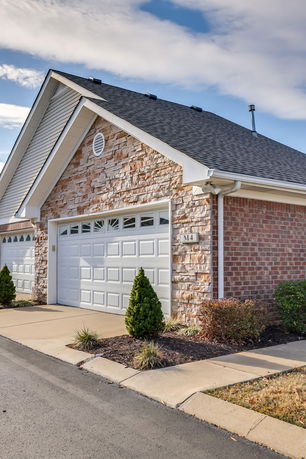 Front view of a garage with a stone façade and white garage doors.