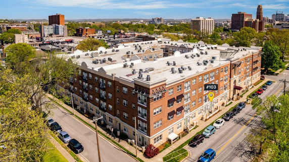 Aerial view of a large multi-story apartment building with a flat roof and multiple air conditioning units.