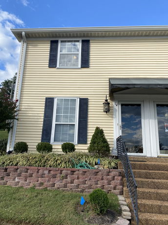 Front view of a two-story house with beige siding and black shutters.