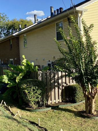 Side view of a two-story house with yellow siding and multiple rooftop vents.