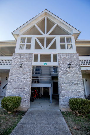 Front view of a two-story building with brick and wood exterior, featuring an external staircase.