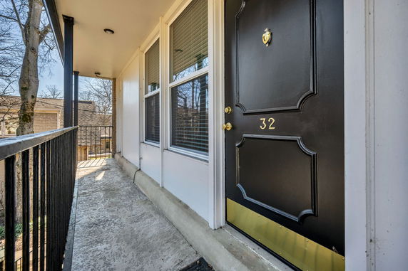 Front view of an apartment entrance with a black door numbered 32 and adjacent windows.