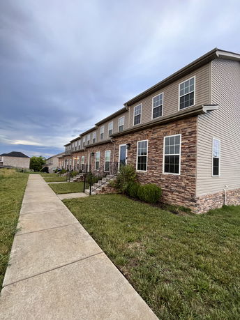 Front view of a row of two-story townhouses with brick and siding exterior.