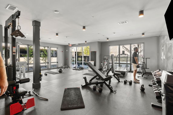 Indoor gym area with various exercise equipment, including weights and machines.