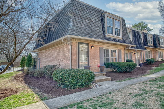 Front view of a townhouse with a sloped roof and brick exterior.