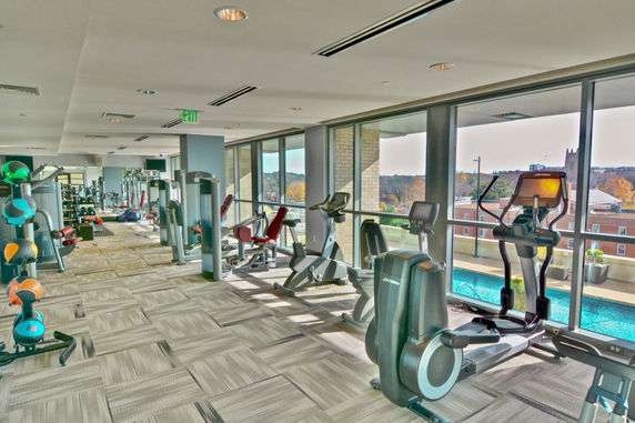 Interior view of a gym with exercise equipment and large windows.