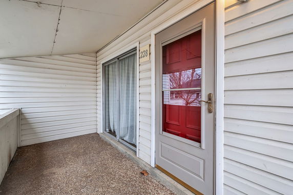Close-up view of a house entrance with a red front door and white siding.