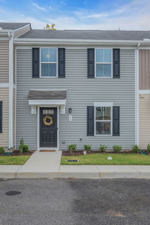 Front view of a two-story townhouse with gray siding and black shutters.