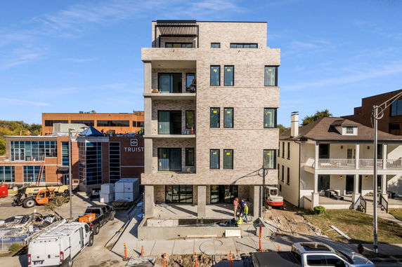 Front view of a multi-story brick building under construction, with large windows and balconies.