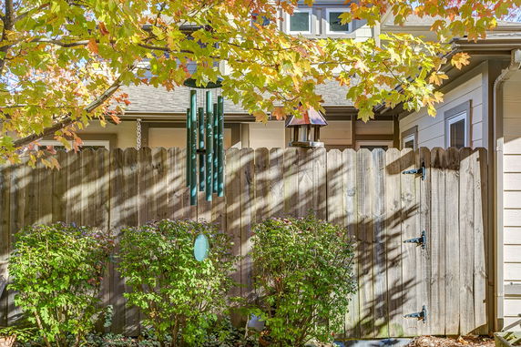 Partial view of a house with a wooden fence and surrounding foliage.