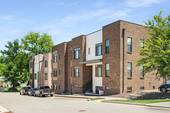 Front view of modern townhouses with brick facade and large windows.