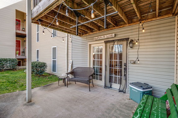 Exterior view of a building's lower level with a patio area and French doors.