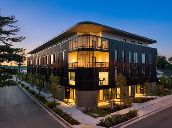 Front view of a modern multi-story building with large windows and a rounded corner design.