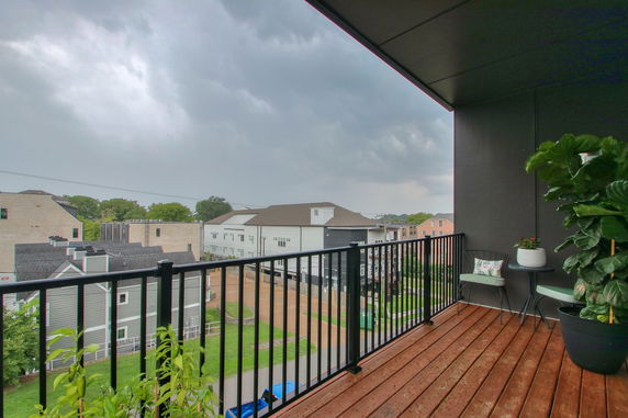 View from a balcony overlooking neighboring residential buildings and a cloudy sky.