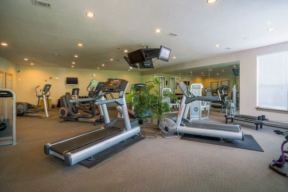 Indoor gym area with exercise equipment and mirrored wall.