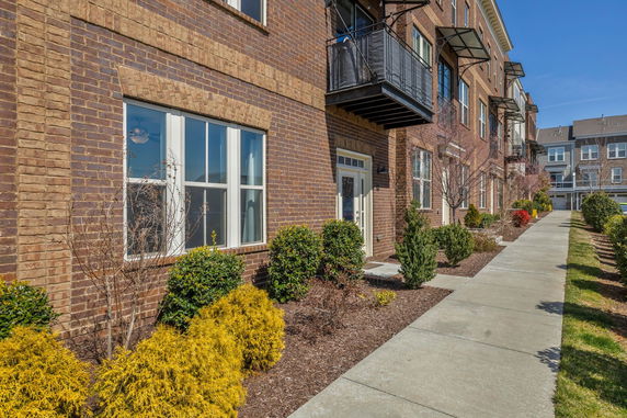 Front view of a multi-story brick building with balconies and large windows.