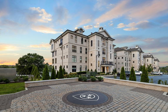 Front view of a multi-story residential building with landscaping and parking area.