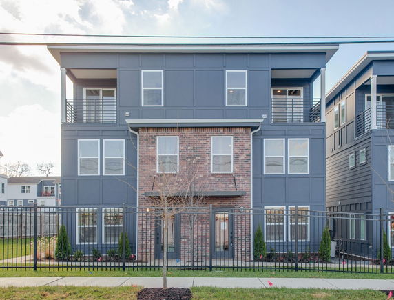Front view of a modern three-story townhouse with a mix of brick and siding exterior.