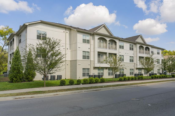 Front view of a multi-story residential building with balconies and a pitched roof.