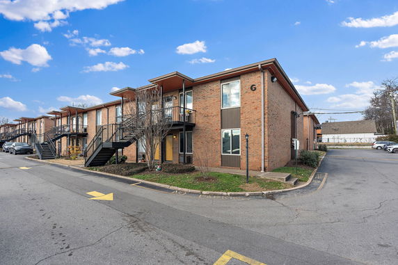 Front view of a two-story brick apartment building with external staircases.