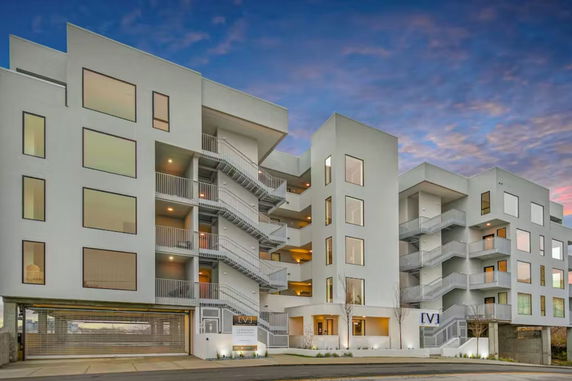 Front view of a multi-story modern apartment building with large windows.