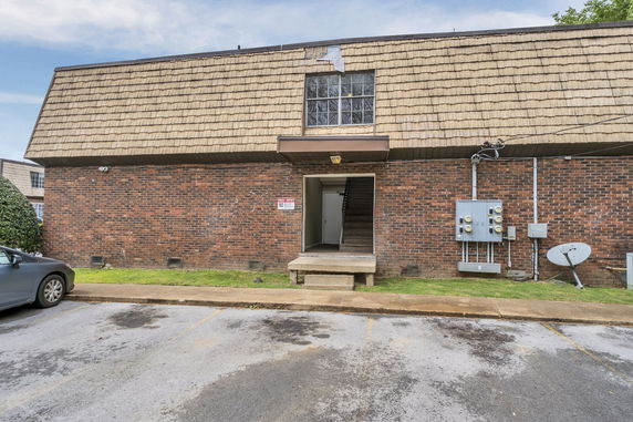 Front view of a two-story brick building with shingle roofing and an open entrance.