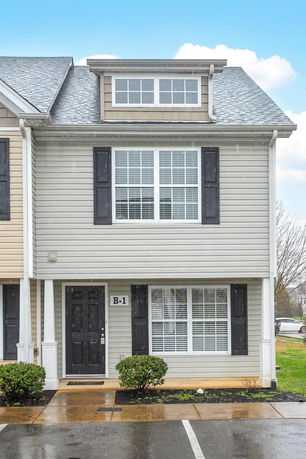 Front view of a two-story townhouse with a dormer window and a black front door.