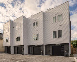 Front view of a modern multi-story townhouse building with garages.