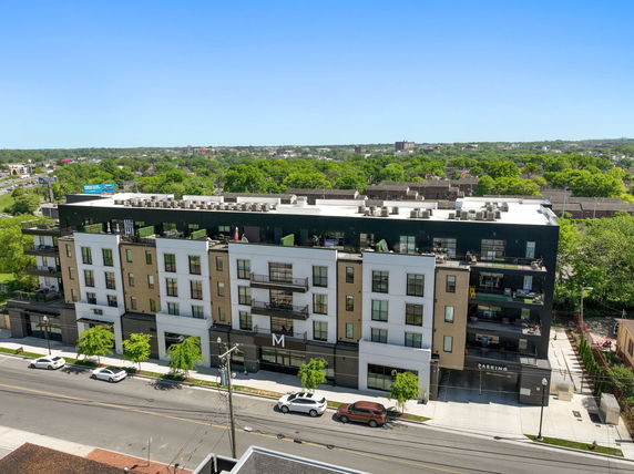 Front view of a multi-story building with balconies and parking area.