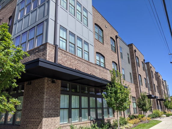 Front view of a multi-story apartment building with brick and panel facade.
