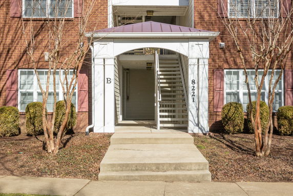 Front view of a multi-story building with an archway and stairs.